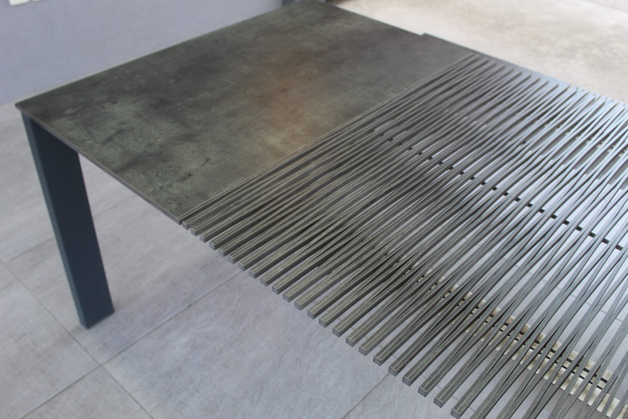 The outdoor table open: the Compact HPL top, the lamellas and an aluminum leg