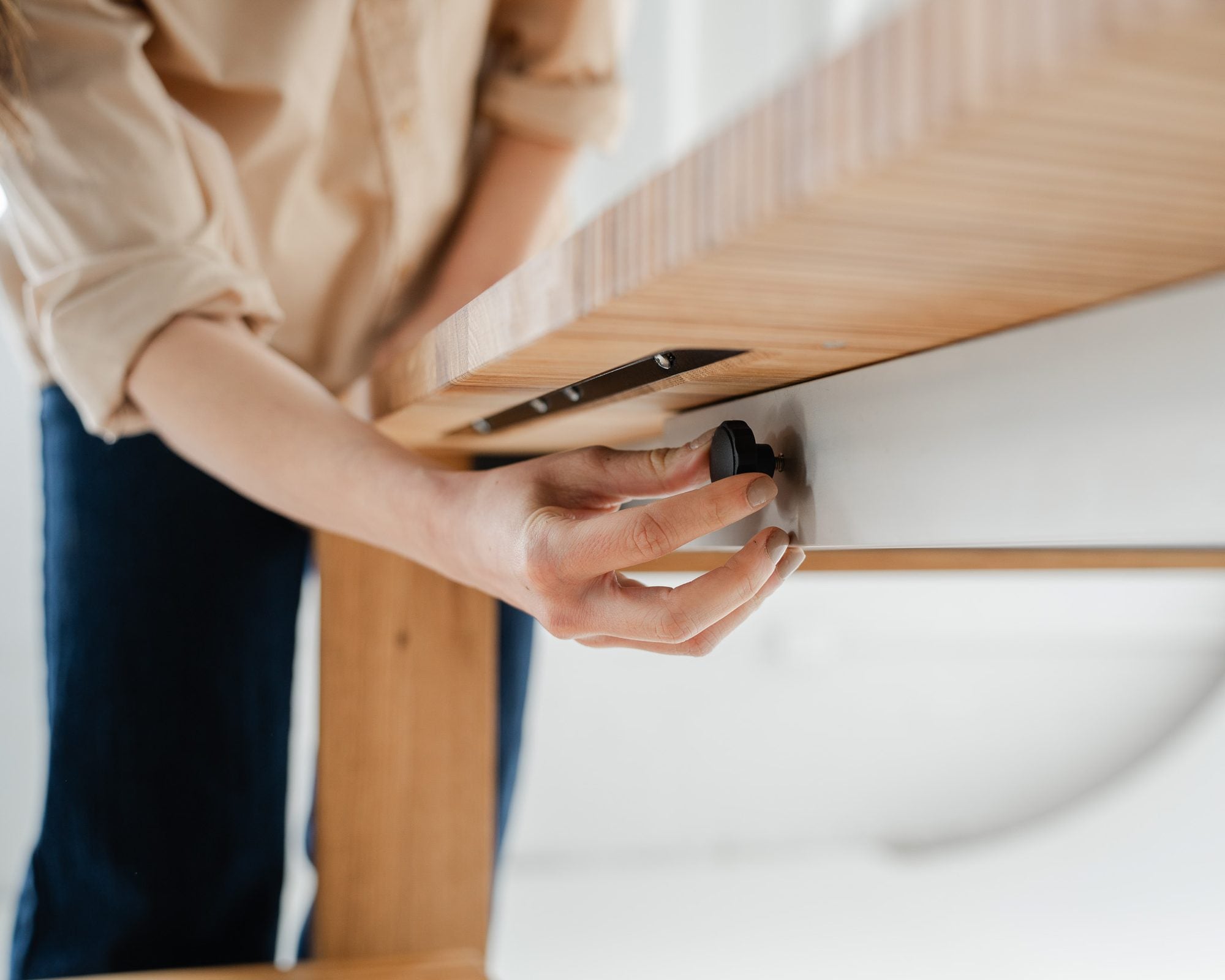 Hands turning the locking wheel under the tabletop