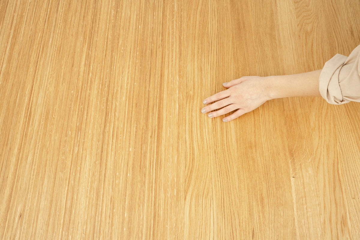 A hand resting on the grain of an oiled oak tabletop