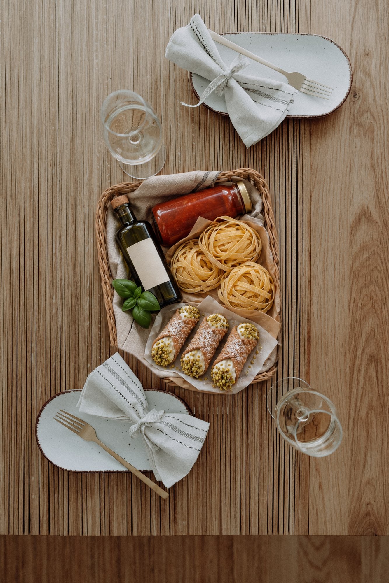 A welcome basket of olive oil, tomato passata, fresh tagliatelle and cannoli on the oak Accordion Table